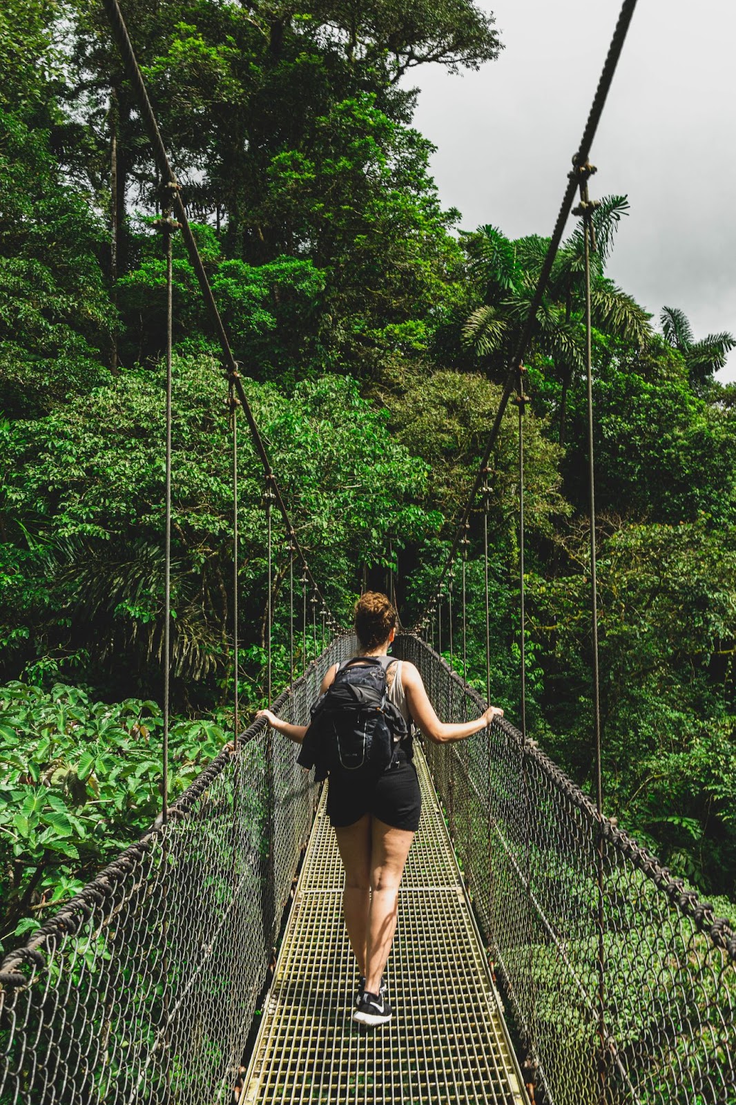 Is It Safe to Travel in Costa Rica Image: Two travelers walk across a jungle suspension bridge.