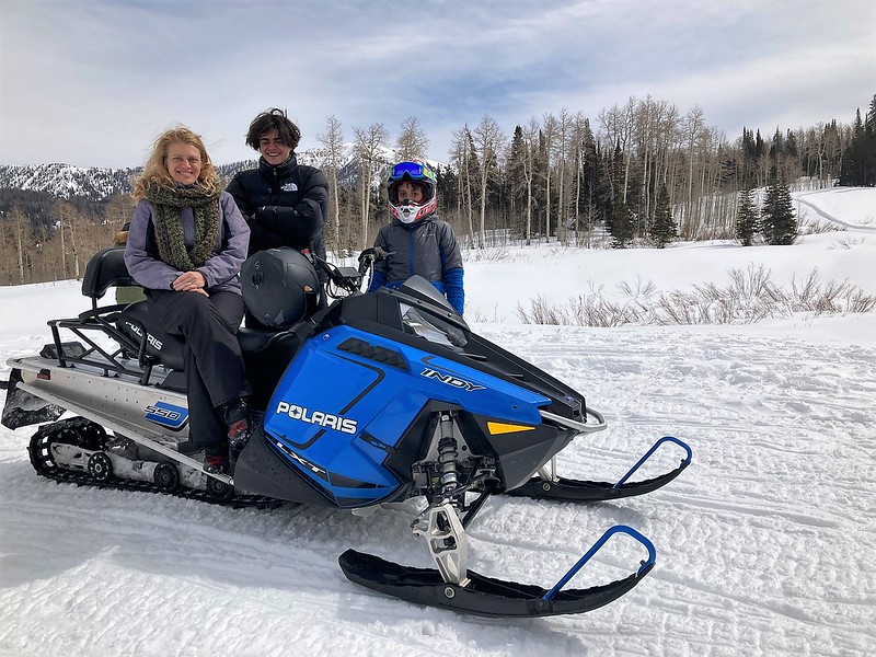 mom and two son teens with a snowmobile on the snow in utah