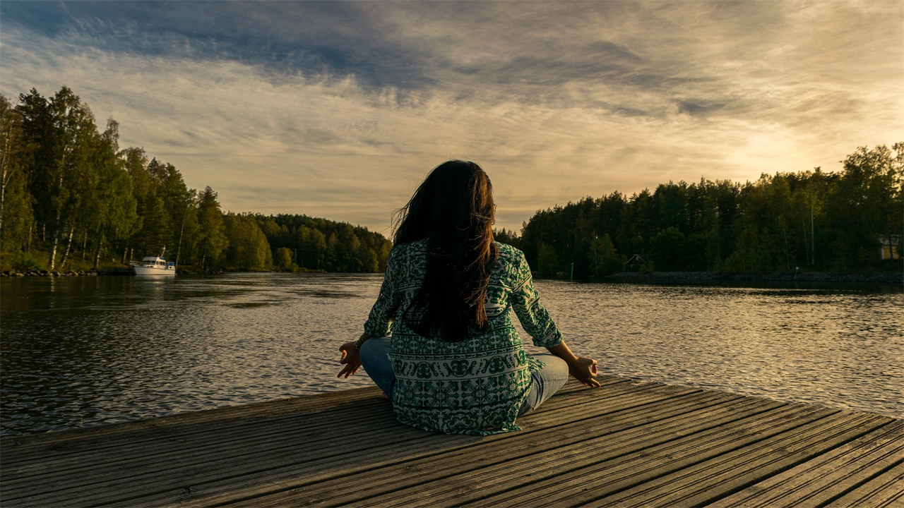 woman sitting on  alake's wooden dock in a wellness retreat united states