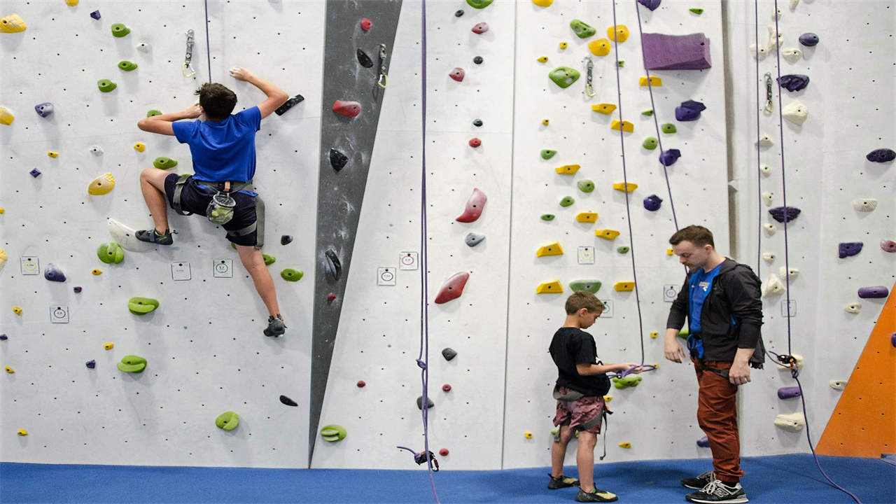 two kids and a instructor at a indoor climbing