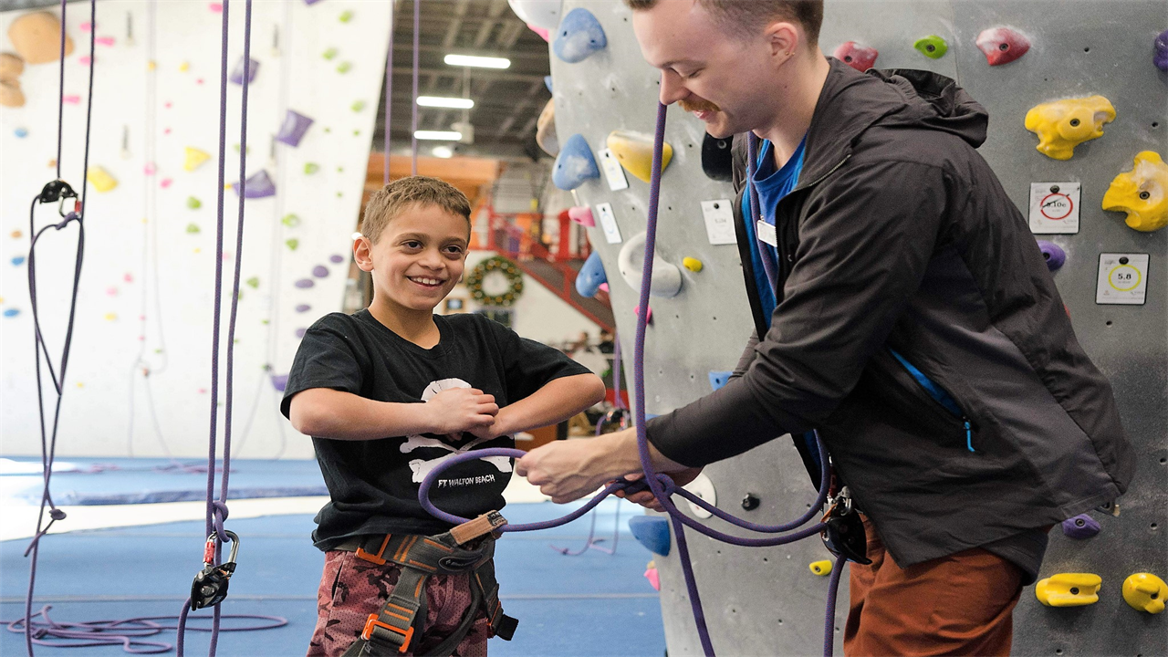 kid getting ready for climbing with a trainer