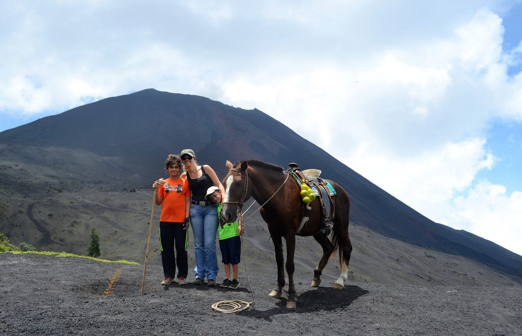 woman and kids next to a horse while hiking pacaya volcano