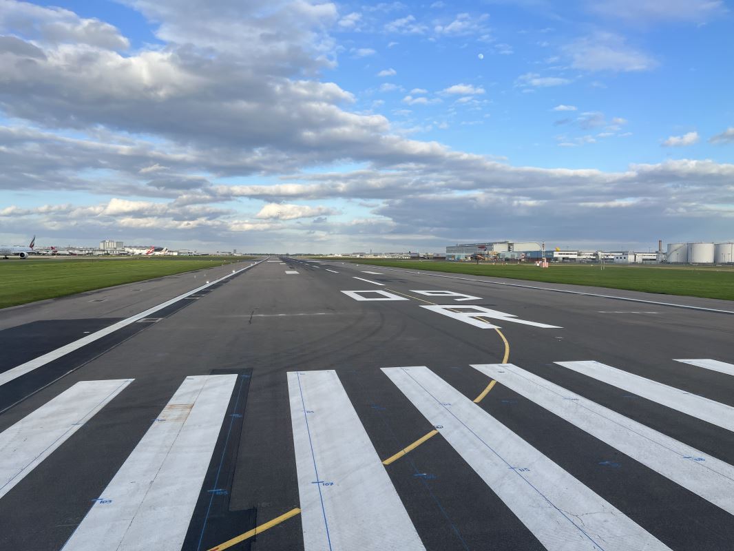 a runway with grass and buildings in the background