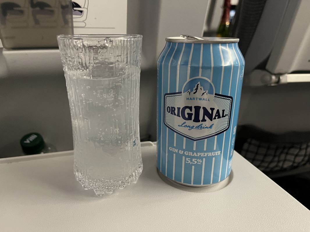 a can of liquid next to a glass of water